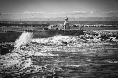 Lighthouse by sea against sky