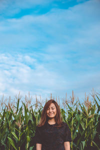 Smiling beautiful woman with eyes closed standing at farm against sky