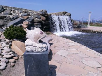 Statue by fountain against clear sky