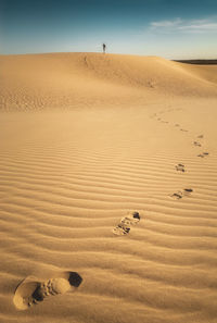 Scenic view of sandy desert with footprints of person walking