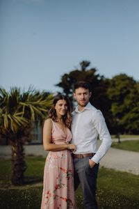 Portrait of young couple standing against sky