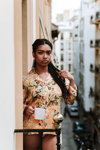 Portrait of young woman standing against wall