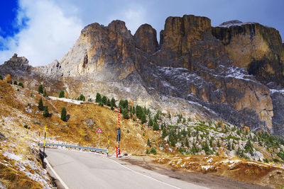 Road by rocky mountains against sky