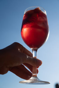 Close-up of hand holding ice cream against sky