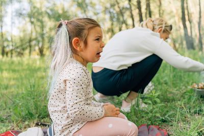 Side view of young woman sitting on field