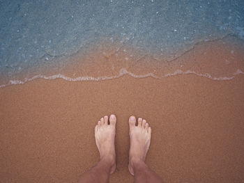 Low section of man standing at beach