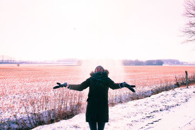Portrait of woman standing on snow covered field against clear sky