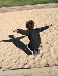 High angle view of boy with shadow on sand