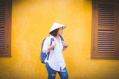 Full length of woman standing against yellow wall