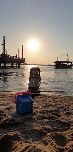 Ship on beach against sky during sunset