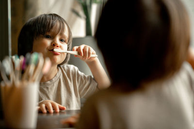 The boy brushes his teeth with a toothbrush made of ecological material