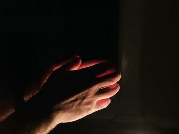 Cropped hand of person holding hands against black background