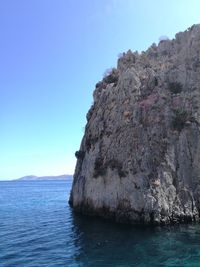 Rock formation in sea against blue sky