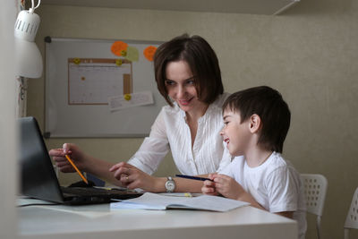 Happy mother is engaged in a laptop with her son preschooler, a real european interior, 