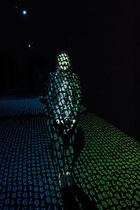 Rear view of man standing against illuminated lights at night