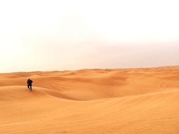 Man walking in desert against clear sky