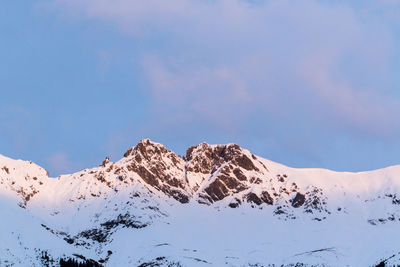 Low angle view of snowcapped mountains against blue sky