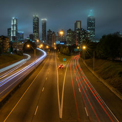 Light trails on road against sky at night