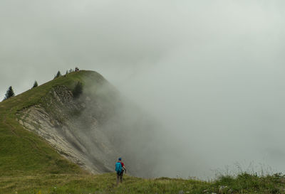 Rear view of man on mountain against sky