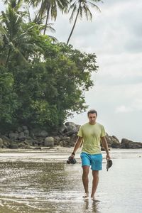 Full length of man standing on coastline  against sky