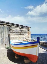 Boat moored on beach against sky