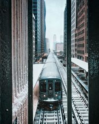 Railroad tracks amidst buildings in city during winter