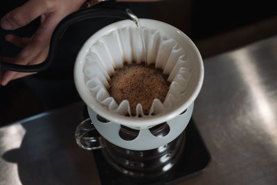 High angle view of hand holding coffee cup on table