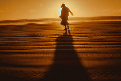 Shadow of man on beach during sunset