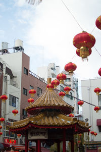 Low angle view of lanterns hanging by building against sky