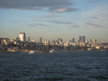 Sea by buildings against sky in city