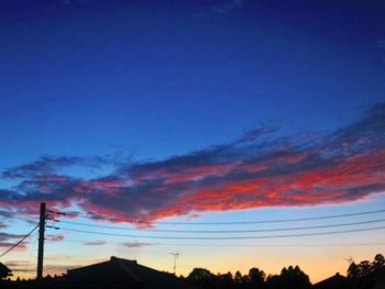 Low angle view of silhouette electricity pylon against sky during sunset