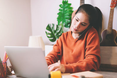 Young woman using phone while sitting on table