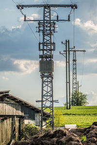 Low angle view of communications tower on field against sky