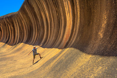 Man standing with arms outstretched by cliff