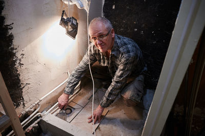 High angle portrait of man installing tiles at bathroom