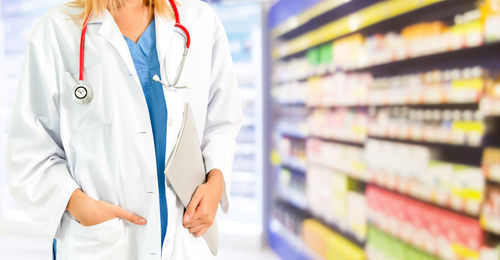 Rear view of doctor with stethoscope standing in pharmaceutical store 