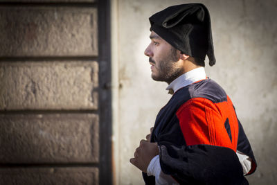 Side view of young man looking away against wall