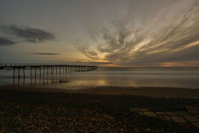 Scenic view of calm sea with pier at sunset