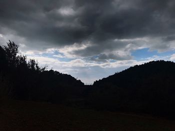 Silhouette of trees against cloudy sky