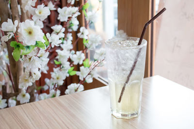 High angle view of drink served on wooden table by white flowers in restaurant