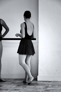 Rear view of young ballet dancer standing against wall