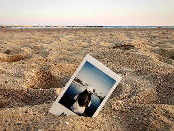 Close-up of open book on beach against sky