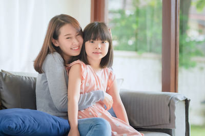 Happy mother and daughter sitting on sofa