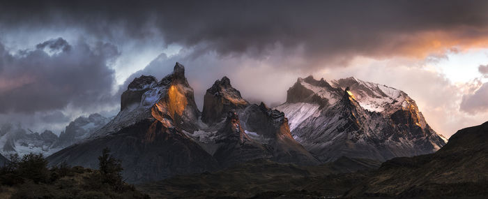 Low angle view of majestic rocky mountains against cloudy sky during sunset