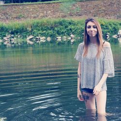 Portrait of young woman smiling while standing in lake