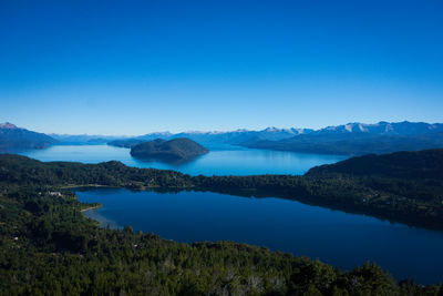 Scenic view of lake and mountains against clear blue sky