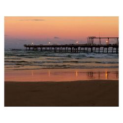 Scenic view of beach against clear sky during sunset