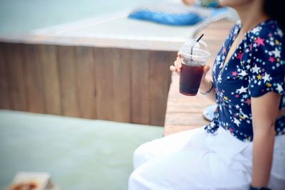 Midsection of woman drinking water in swimming pool