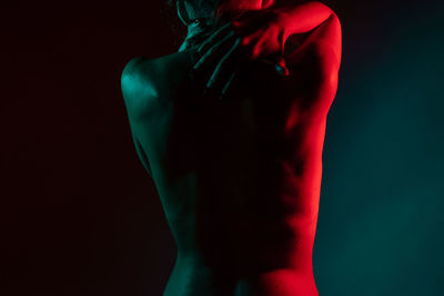 Rear view of shirtless man against black background