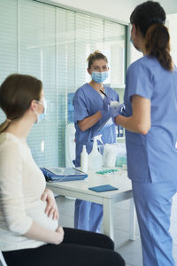 Side view of doctor giving medicine to colleagues in office